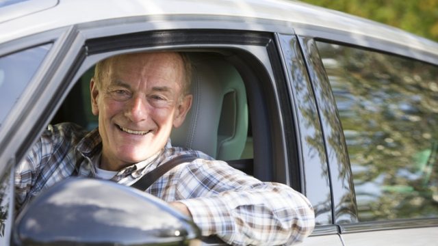 Portrait Of Smiling Senior Man Driving Car